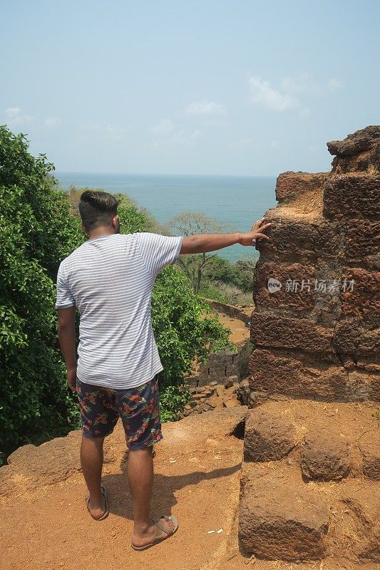 一名印度男子站在Cabo De Rama堡垒废墟上俯瞰大海，印度果阿